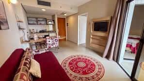 Un salon avec un canapé, un téléviseur, un coin cuisine et une chambre à coucher avec un lit.