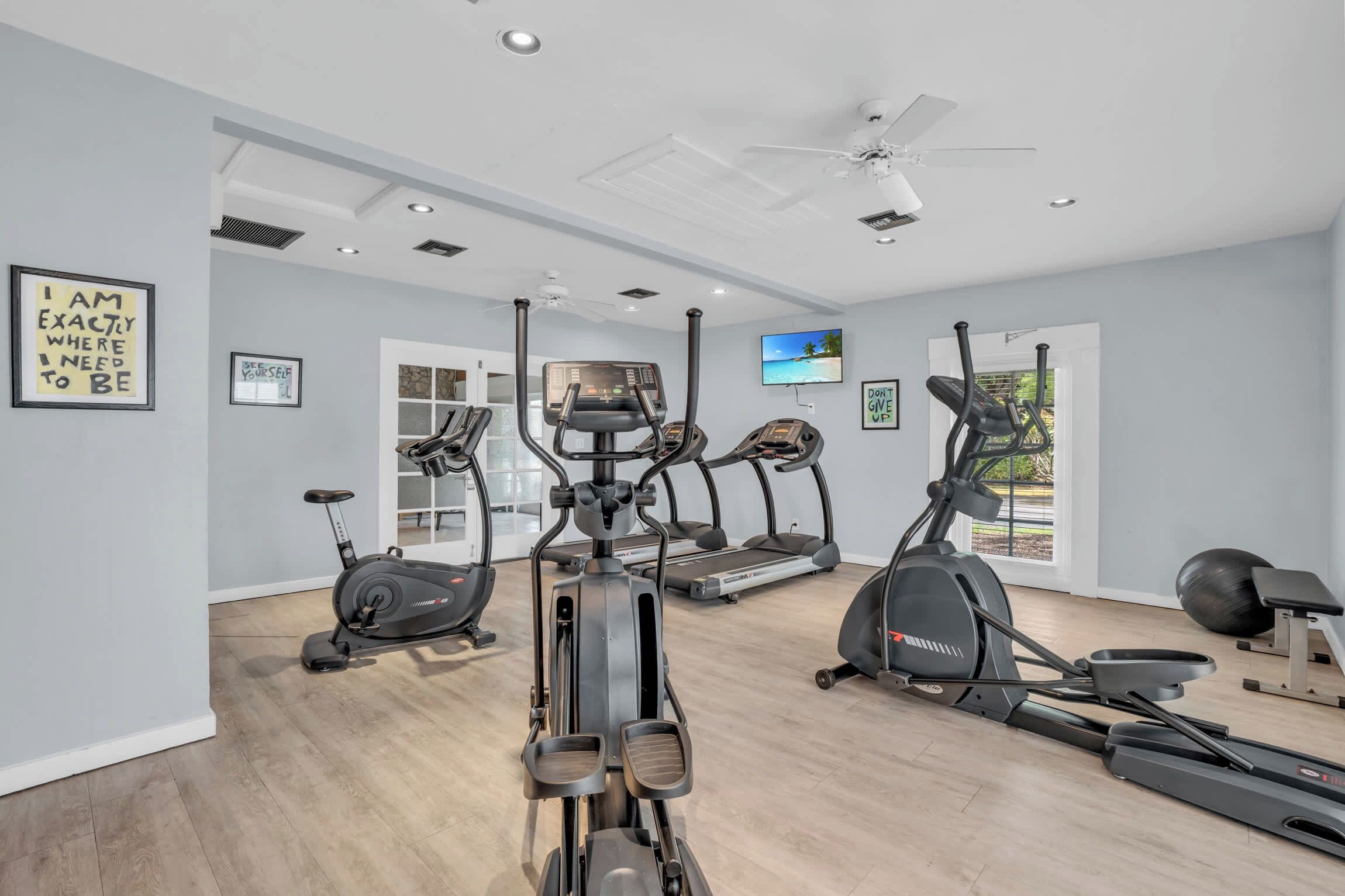 Une salle de sport à domicile équipée de tapis de course, de vélos elliptiques et d’un vélo d’appartement.