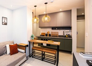 Une cuisine moderne dotée d’un îlot central, de luminaires suspendus et d’une banquette pour prendre les repas.