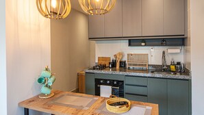 A modern kitchen with dark cabinets, a granite countertop, and two pendant lights. - SHB • Praiamar Shopping | Beach Just Steps Away (Santos)