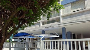 A hotel with a gated entrance, a covered outdoor area, and a building with blue-tiled balconies. - SHB - Maritime Comfort: Studio with Sea View (Santos)