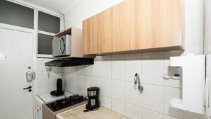 A compact kitchen with a built-in microwave, a coffee maker, a sink, and wooden cabinets. - SHB - Maritime Comfort: Studio with Sea View (Santos)