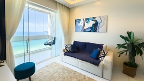 A modern living room with a sofa, a chair, a large window with a view of the sea, and a painting on the wall. - SHB - Wake Up to the Blue of the Sea at Your Window! (Guarujá)