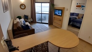 Ein modernes Hotelzimmer mit großem Fenster, einem Flachbildfernseher, einem Essbereich und einem Balkon mit Blick.