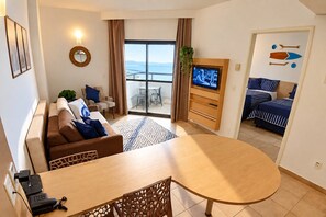 A hotel room with a balcony, a dining area, a TV, and a bed with striped bedding. - SHB - On the Sand, Pool, Amazing View (Santos)