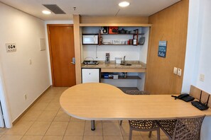 Eine kleine Küche mit Mikrowelle, Herd und Spüle, einem Holztisch und einem Stuhl.