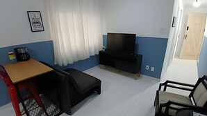 Ein gemütlicher Wohnbereich mit Fernseher, einem kleinen Tisch, einer Couch und einem Sessel.
