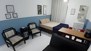 Ein modernes Hotelzimmer mit einem Bett, zwei Sesseln, einem Tisch und einem Schreibtisch.