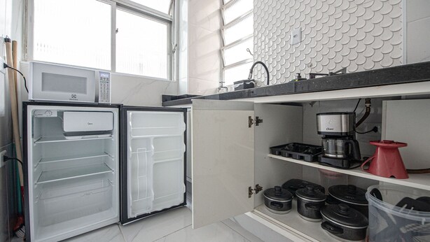 Eine Küche mit Mikrowelle, Kühlschrank, Kaffeemaschine und verschiedenen Küchenutensilien.