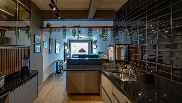 Una cocina moderna con una isla central, suelo de madera y plantas colgantes.
