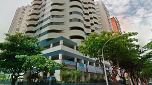 A multi-story building with a curved facade, balconies, and signage indicating commercial use. - SHB - The Best of Pitangueiras with Beach Service (Guarujá)