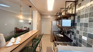 A modern kitchen with a long counter, green chairs, a built-in stove, and a microwave. - SHB - The Best of Pitangueiras with Beach Service (Guarujá)