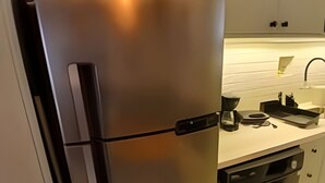 Un réfrigérateur en acier inoxydable doté d’une poignée noire, d’une machine à café intégrée et d’un lave-vaisselle.