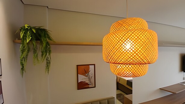 Un intérieur moderne agrémenté d’une suspension orange, d’une plante verte et d’une œuvre d’art encadrée au mur.