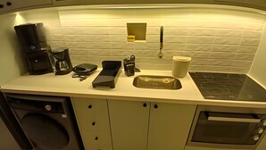 Une petite cuisine équipée comprenant une machine à café, une balance, une bouilloire et un four à micro-ondes.