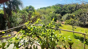 Un espace extérieur abrité, doté d’un plafond en bois et offrant une vue sur un paysage verdoyant luxuriant.