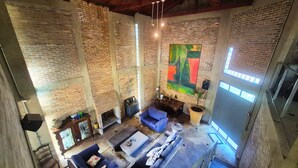 Un vaste loft aux murs en briques apparentes, agrémenté d’un grand tableau abstrait et doté d’une mezzanine aménagée en espace détente.
