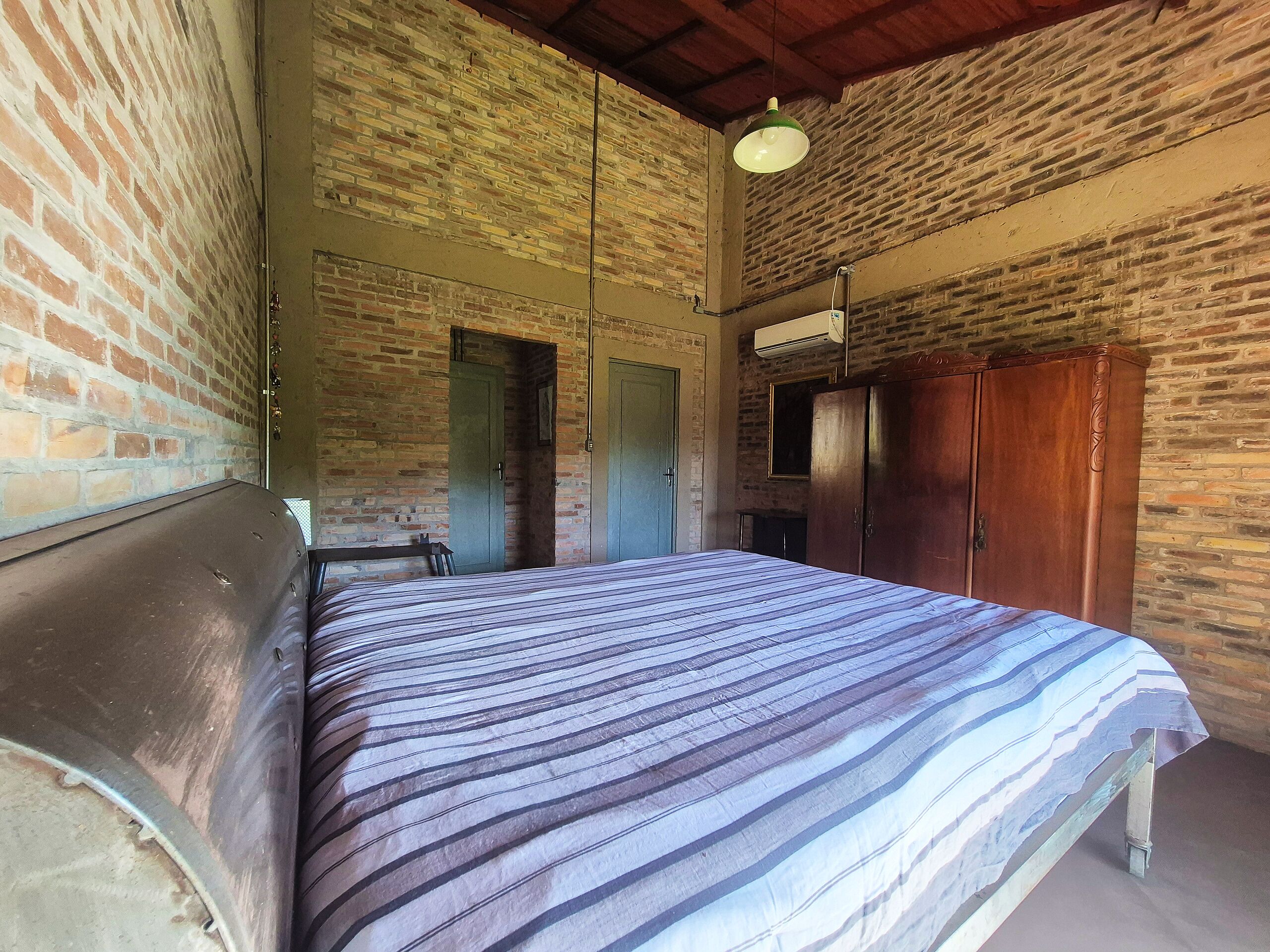 A room with a bed, a wardrobe, and a brick wall.