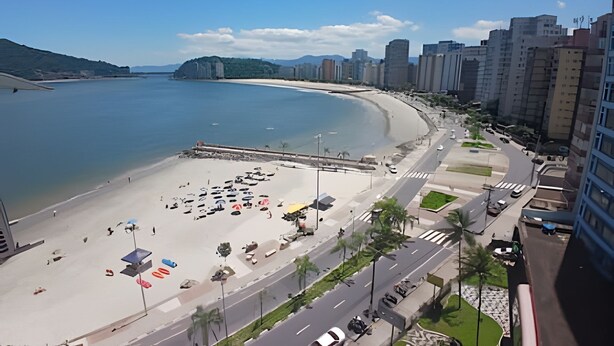 A coastal cityscape with a beach, high-rise buildings, and a road with vehicles.