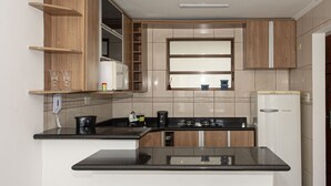 A compact kitchen with a central island, wooden cabinets, and a built-in microwave.