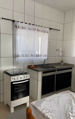 Een koelkast, een oven, kookgerei, borden en bestek