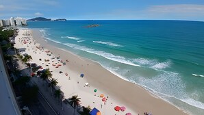 A beach with a clear view of the ocean, a sandy shore, and a distant mountain. - SHB - Amazing view | On the Sand | Pitangueiras (Guarujá)