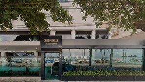 The exterior of Chop Hall Restaurant with a modern design, large glass windows, and a paved entrance area. - SHB - Amazing view | On the Sand | Pitangueiras (Guarujá)