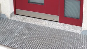 A red door with a glass panel, a metal handle, and a mail slot with labels. - Pension Antje Ekert (Uhldingen-Muehlhofen)