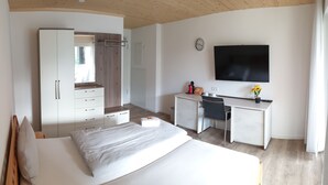 A modern bedroom with a bed, a desk, and a TV. - Pension Antje Ekert (Uhldingen-Muehlhofen)