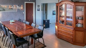 A dining area with a wooden table and chairs, a cabinet with glass doors, and hanging pendant lights. - 3 bedroom cozy home in Bøvlingbjerg (Bøvlingbjerg)