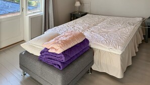 A neatly made bed with a white mattress and a grey upholstered bench with folded blankets. - 3 bedroom cozy home in Bøvlingbjerg (Bøvlingbjerg)
