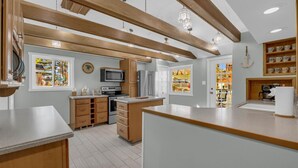 A modern kitchen with wooden beams, a central island, and a view of a garden through the window. - The Lakeview Lookout - Gorgeous Lake Views! (Lexington)