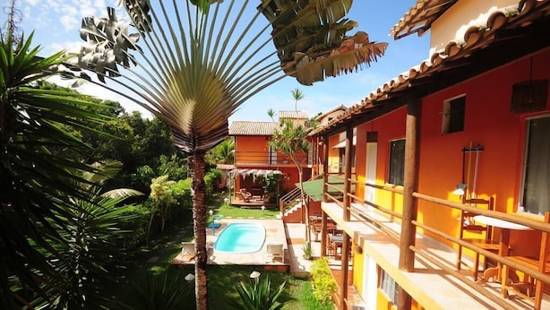 A hotel with a pool, outdoor seating, and lush greenery. - Mandacaru Pousada (Porto Seguro)