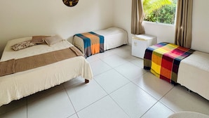 A room with a bed, a sofa, a ceiling fan, a window with curtains, and a wall-mounted air conditioner. - Mandacaru Pousada (Porto Seguro)