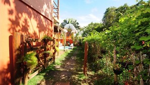 A narrow pathway leading to a building with a red exterior and a wooden fence on the left. - Mandacaru Pousada (Porto Seguro)