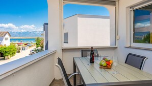 Ein Balkon mit Esstisch, einer Weinflasche und einer Obstschale.