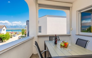 A balcony with a table set for dining, a bottle of wine, and a fruit bowl. - Nice apartment in Vir with WiFi (Vir)
