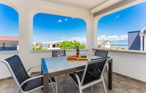 Ein Balkon mit Tisch für zwei Personen, einer Weinflasche und einer Obstplatte.