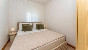 Ein Schlafzimmer mit einem Bett, zwei Nachttischen und einem Vorhangfenster.