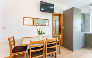 A dining area with a table and chairs, a television mounted on the wall, and a mirror above the table. - Nice apartment in Vir with WiFi (Vir)