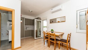 Un espacio habitable compacto con comedor, cocina y un pequeño balcón.