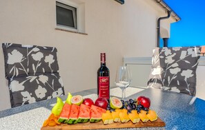 Una mesa con una botella de vino, copas y una bandeja de fruta.