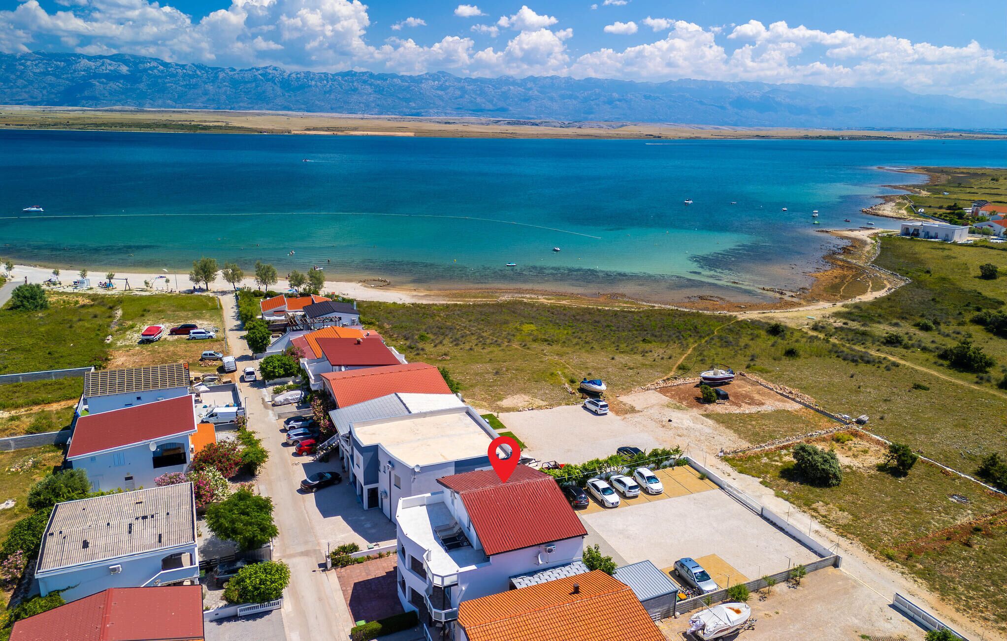 Vista aèria d'una zona costera amb edificis, un pàrquing i una gran massa d'aigua.