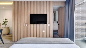 Ein modernes Hotelzimmer mit einem großen Bett, einem Wandfernseher und einer Topfpflanze.