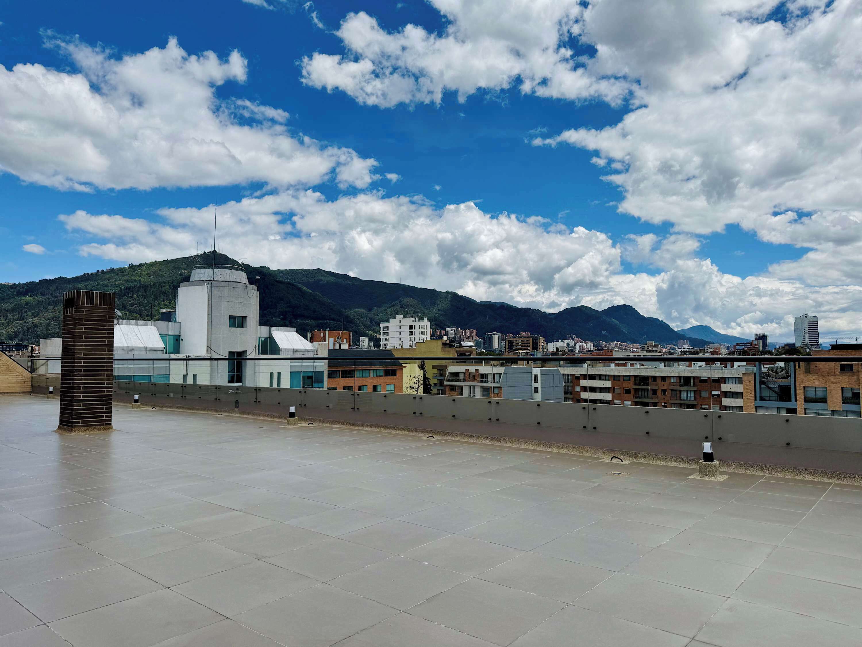 A rooftop terrace with a view of a cityscape and mountains.