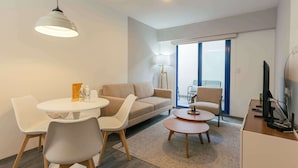 Una sala de estar moderna con una mesa redonda de comedor, un sofá, una mesa baja y un televisor.