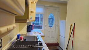 Eine Küche mit Spüle, Arbeitsplatte und einer Tür, die auf einen Balkon führt.