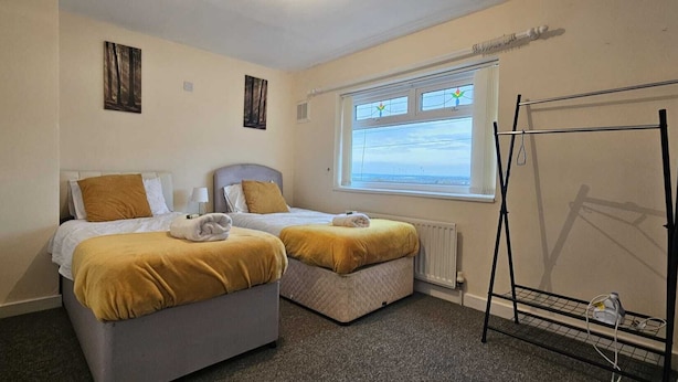 Ein Zimmer mit zwei Betten, einem Fenster mit Aussicht, einem Heizkörper und einem Wäscheständer.