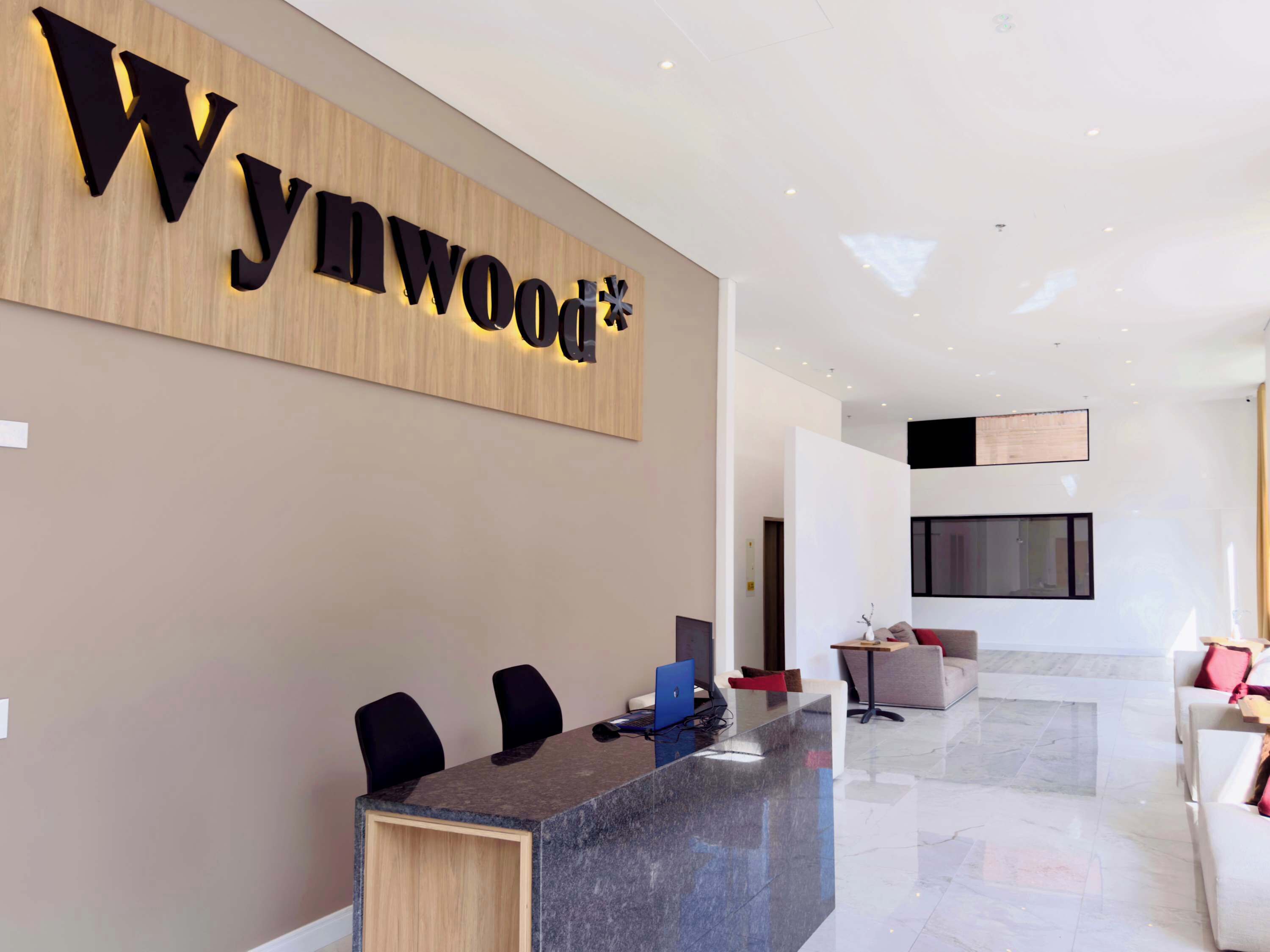 A modern reception area with a wooden wall displaying the name 'Wynwood'.