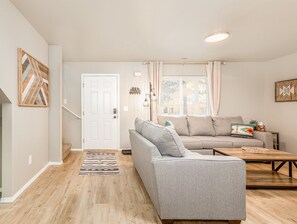 A living room with a grey sofa, a wooden coffee table, and a patterned rug. - Modern Comfort with Western Flair – 3BR/2BA Townhome! (Boise)